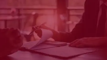 Dwie osoby przy stole, jedna przegląda dokumenty. Czy to lobbysta kto to?