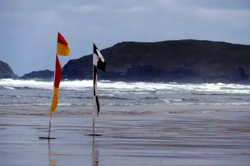 Dwie flagi na plaży: czerwono-żółta i czarno-biała szachownica. Czarna flaga nad morzem oznacza, że kąpiel jest zabroniona.