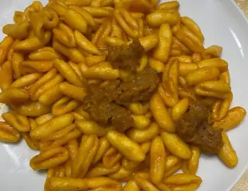 Un piatto invitante di gnocchetti alla campidanese, conditi con un sugo ricco e pezzetti di carne saporita.