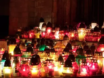 Płonące znicze, symbol modlitwy za zmarłych rodziców, tworzą ciepłe światło wśród ceglanych murów.