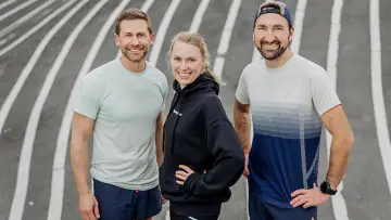 Tre glada löpare på en bana, redo för en bra tid på maraton.