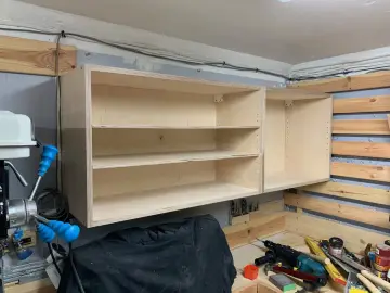 Solidne mocowanie szafek wiszących do ściany za pomocą drewnianych wsporników. Widać narzędzia i materiały do majsterkowania.