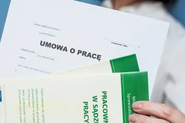 Umowa o pracę, która musi być na czas nieokreślony, leży obok broszury o sprawach pracowniczych.
