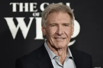Harrison Ford, który ma 81 lat, uśmiecha się na tle napisu "The Call of the Wild".