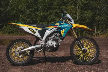 Motocykl crossowy Barton MZK 250 w kolorach niebieskim, żółtym i białym, z żółtymi szprychami.