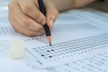 Dłoń z ołówkiem zaznacza odpowiedzi na arkuszu. Zastanawiasz się, ile jest pytań na egzaminie zawodowym?