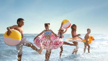 Dzieci bawią się na plaży z dmuchanymi zabawkami, idealny hotel z animacjami dla dzieci.