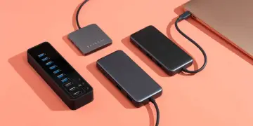 Czarny hub z wieloma portami USB i dwa szare huby Satechi, jeden podłączony do laptopa.