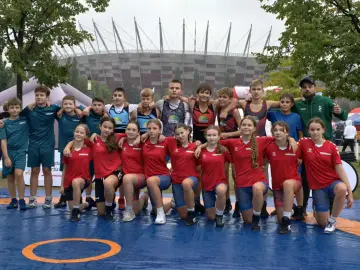 Młodzi zapaśnicy z klasy sportowej w podstawówce pozują do zdjęcia na macie. W tle Stadion Narodowy.