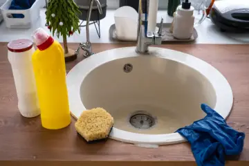 Productos de limpieza y guantes listos para desatascar el fregadero.