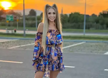 Joanna Narożna w zwiewnej, wzorzystej sukience pozuje na tle zachodzącego słońca.