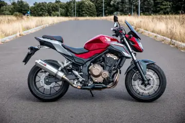 Czerwony motocykl Honda CB 500 F na drodze. Poznaj honda cb 500 f dane techniczne i możliwości tego zwinnego naked bike'a.