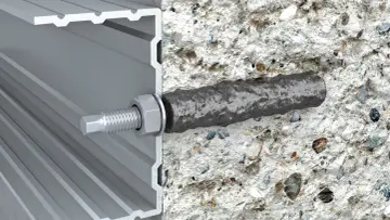 Przekrój profilu aluminiowego z kotwą chemiczną w betonie. Widoczny pręt zbrojeniowy osadzony w betonie, połączony z profilem za pomocą śruby i nakrętki.