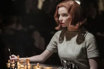 Beth Harmon, z gambitu królowej obsady, skupiona nad szachownicą.