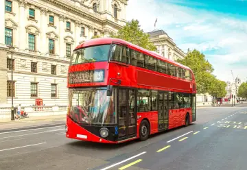 Ikoniczny czerwony autobus piętrowy na ulicy w Londynie, symbol komunikacji miejskiej.