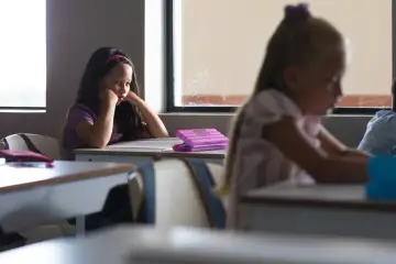 Smutna dziewczynka z opaską na głowie siedzi przy ławce, myśląc o ocenie niedostatecznej na półrocze.