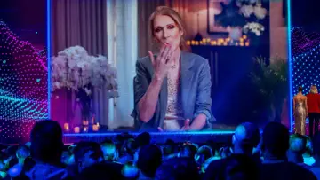 Celine Dion przesyła całusy z ekranu, a publiczność wpatruje się w nią z zachwytem.