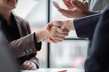 Dwie osoby ściskają sobie dłonie, symbolizując porozumienie. Czy związki zawodowe reprezentują wszystkich pracowników?
