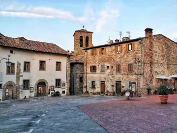 Piazza di un borgo toscano, ideale tra i borghi da visitare in 2 giorni. Edifici in pietra e mattoni, campanile e scorci suggestivi.