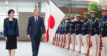 Uroczyste powitanie w Japonii. Polska delegacja z flagami Japonii i honorową asystą wojskową.