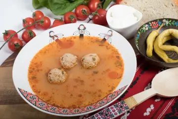 Aromaticzna zupa romana z klopsikami, podana z chlebem, śmietaną i pikantną papryką.
