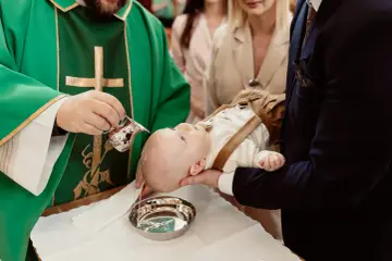 Chrzest dziecka w kościele: kapłan polewa głowę niemowlęcia wodą święconą. To ważny moment, który nie trwa długo.