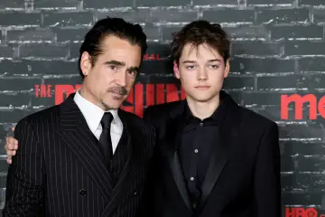 Colin Farrell i jego syn, Barry Keoghan, pozują do zdjęć. Colin ma na sobie prążkowany garnitur, a jego syn czarny smoking.
