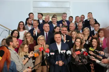 Grupa posłów Polski 2050, w tym Szymon Hołownia, otoczona przez dziennikarzy z mikrofonami.