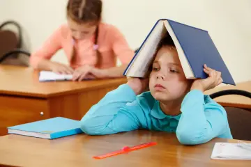 Chłopiec z książką na głowie, szukający sposobu, jak wyciszyć przestymulowane dziecko.