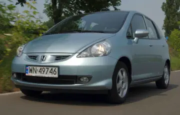 Jasnoniebieski Honda Jazz 2 na drodze, z zielenią w tle.