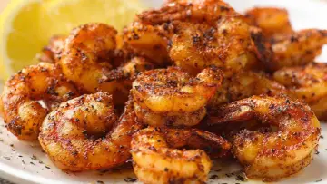 Pyszne krewetki z airfryer, przyprawione i lekko przypieczone, z plasterkiem cytryny w tle.