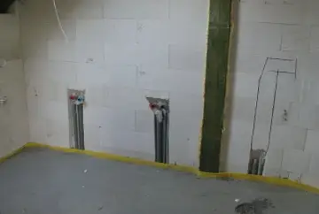 Ściana z bloczków z widocznymi bruzdami pod kable i instalacją wodną. Przygotowania do montażu urządzeń.