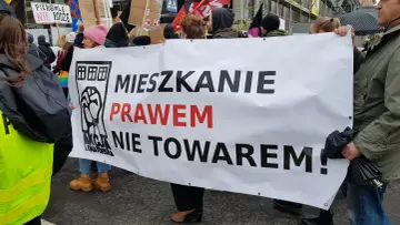 Protestujący niosą transparent "Mieszkanie prawem nie towarem!", domagając się ustaw chroniących lokatorów.