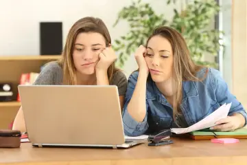 Dwie znudzone nastolatki przy laptopie, zmęczone nauką zdalną.