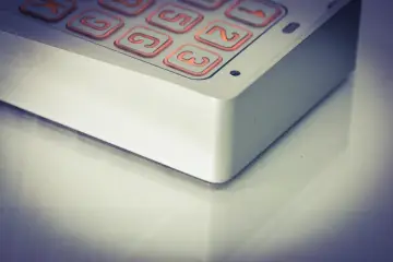 Zbliżenie na klawiaturę domofonu z podświetlanymi na pomarańczowo przyciskami z cyframi.