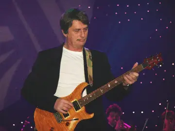 Muzyk grający na gitarze, przypominający styl Mike'a Oldfielda. Koncertowa atmosfera z fioletowym tłem i świetlnymi akcentami.