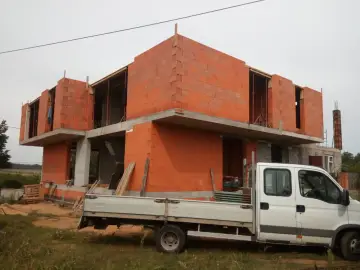Budowa domu z cegły ceramicznej, gotowego do tynkowania. Zastanawiasz się, ile trwa tynkowanie domu? To zależy od wielu czynników, ale ten etap budowy jest kluczowy.