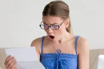 Zaskoczona kobieta w okularach czyta dokument. Czy to wypowiedzenie umowy zlecenia?