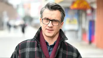 Michał Czernecki w okularach i płaszczu w kratę, gotowy do kolejnych filmów, seriali i programów.
