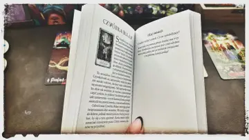 Mistycyzm i tarot marzyciela: otwarta księga z kartą "Czwórka Buław" i innymi kartami tarota.