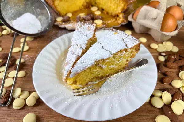 Fette di caprese al limone spolverate di zucchero a velo, con mandorle e gocce di cioccolato bianco.