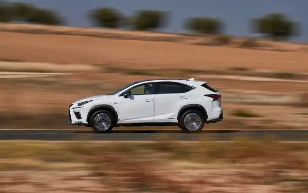 Biały suv Lexus NX 350h jedzie po pustynnej drodze, rozmywając krajobraz.