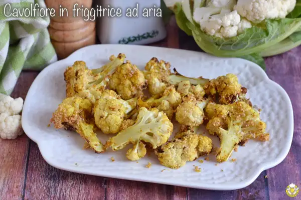Cavolfiore dorato e croccante, cotto in friggitrice ad aria, servito su un piatto bianco.