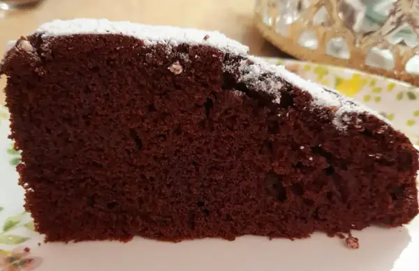 Una fetta di torta al cioccolato soffice, spolverata di zucchero a velo. Un'idea golosa per una torta mascarpone e cioccolato.