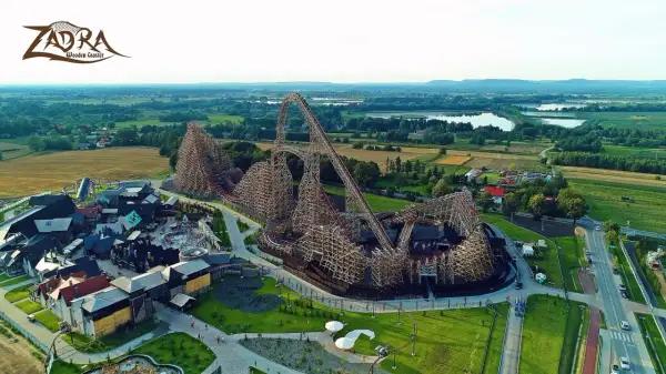 Drewniany rollercoaster Zadra w parku rozrywki, z widokiem na okoliczne pola i jeziora. Zastanawiasz się, ile jedzie Zadra?