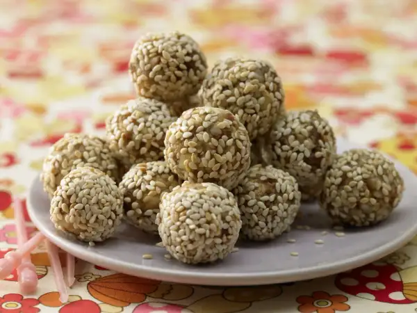 Ein Haufen köstlicher Energy Balls, umhüllt von Sesam, auf einem Teller. Perfekt für einen schnellen Energieschub!