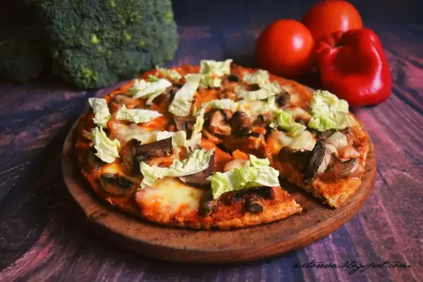 Pyszna pizza z twarogu z pieczarkami i kapustą pekińską, obok brokuły i pomidory.
