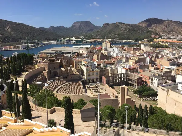 Vista panorámica de Cartagena, con el teatro romano y el castillo de la Concepción dominando el paisaje urbano y el puerto.