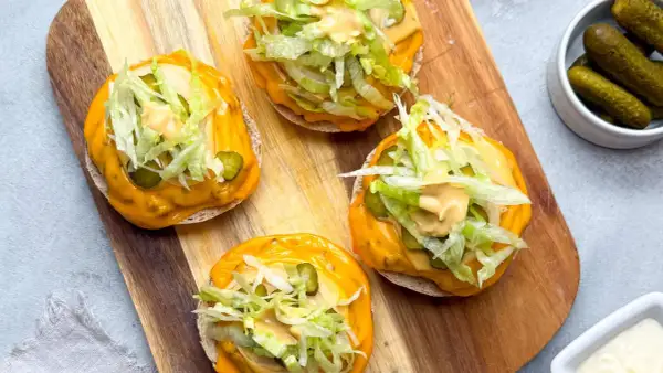Vier offene **Big Mac Rollen** mit Käse, Salat, Gurken und Sauce auf einem Holzbrett.