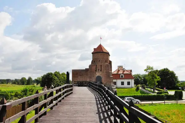 Drewniany most prowadzi do ceglanego zamku z czerwoną wieżą. Idealne miejsce na weekendowe wypady, to jedne z fajnych miejsc niedaleko Warszawy na weekend.